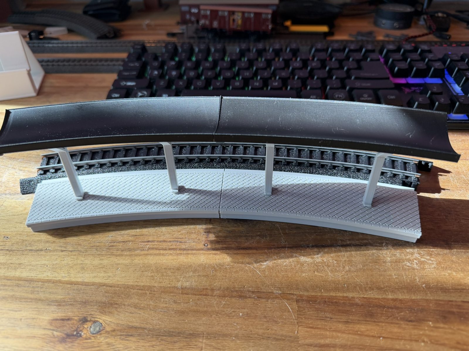 Real print: two curved station modules with pillars and black canopy along a Power-Loc 22 in curve